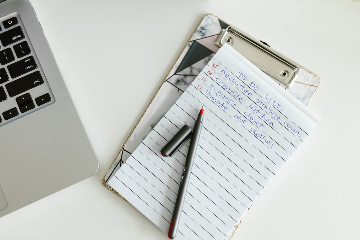 A neatly organized to-do list on a clipboard next to a laptop and pen
