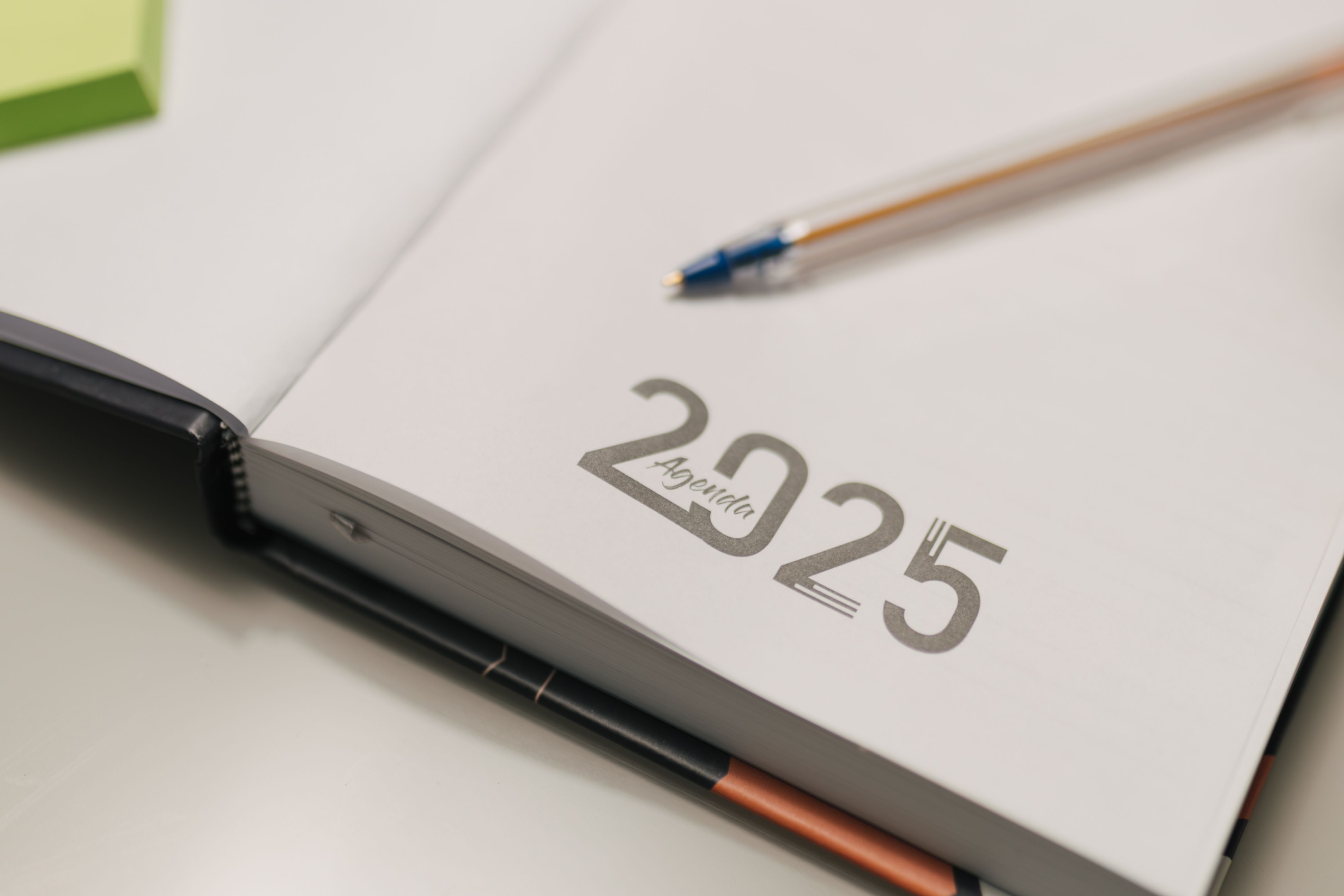 An open desk planner with a pen, representing predictable monthly planning