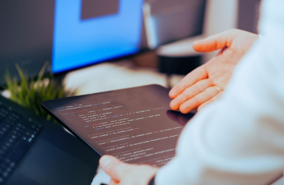 A developer closely reviewing lines of code on a tablet