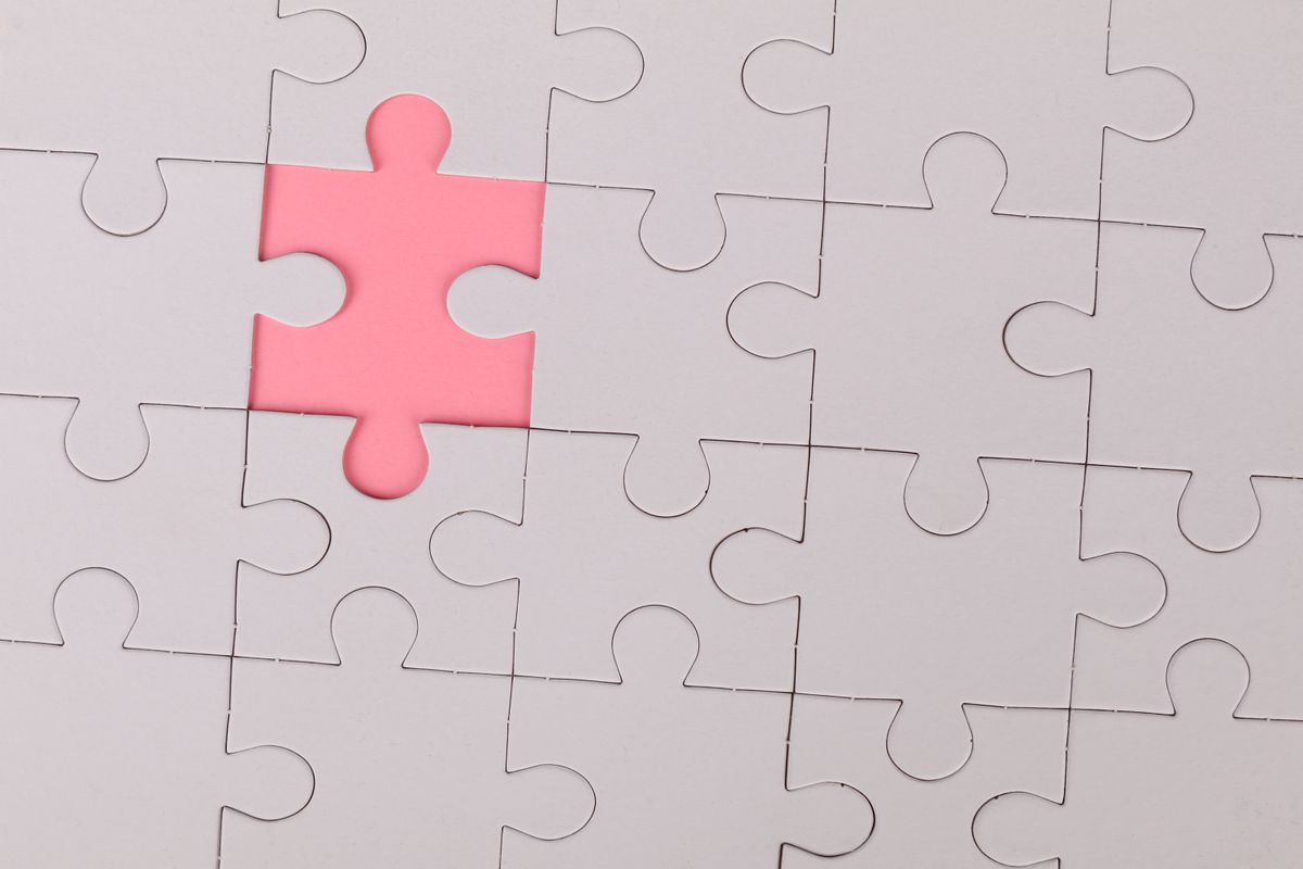 An unfinished jigsaw puzzle with one pink piece missing