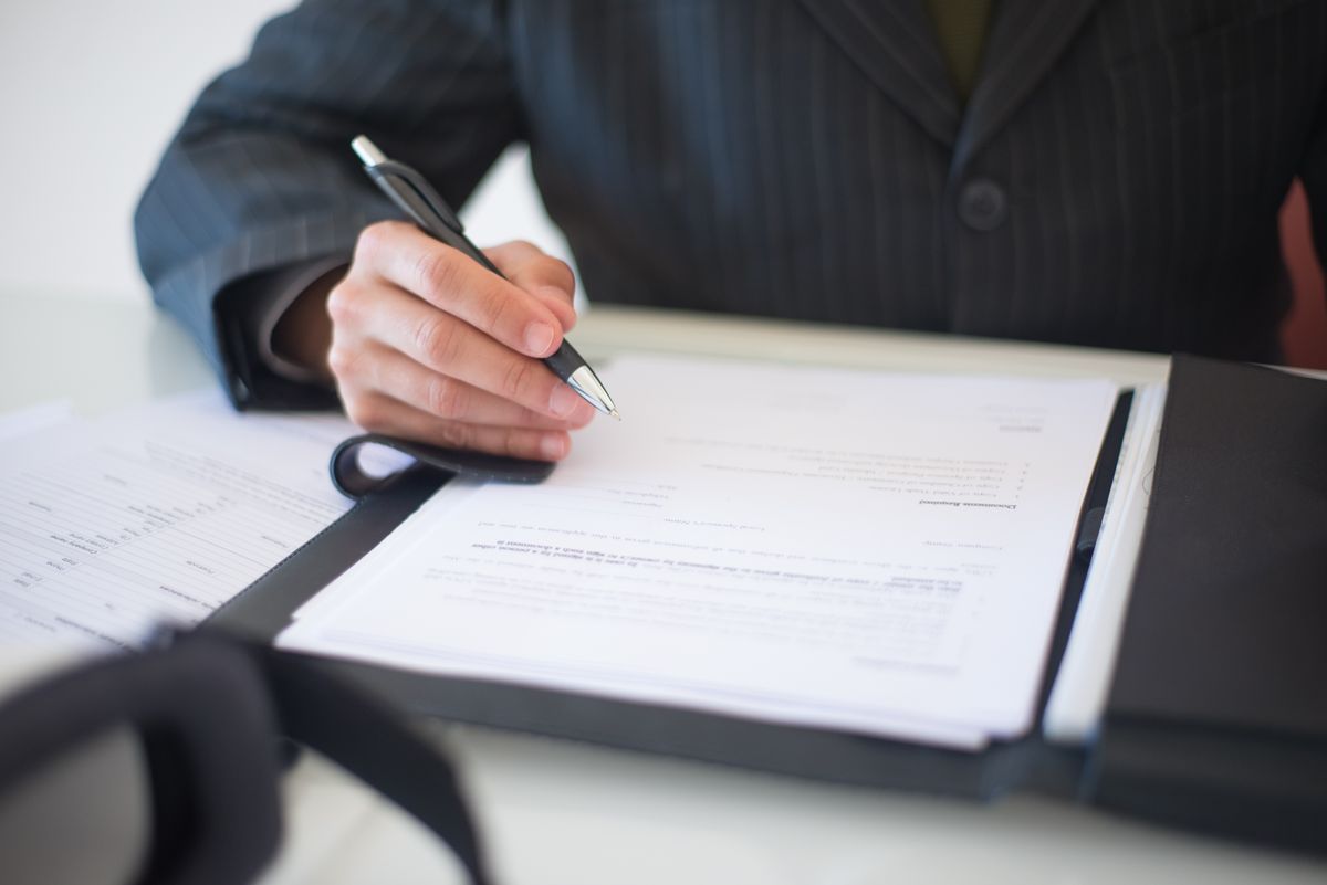 Close-up of a hand signing a business contract with a pen, symbolizing the terms behind a subscription