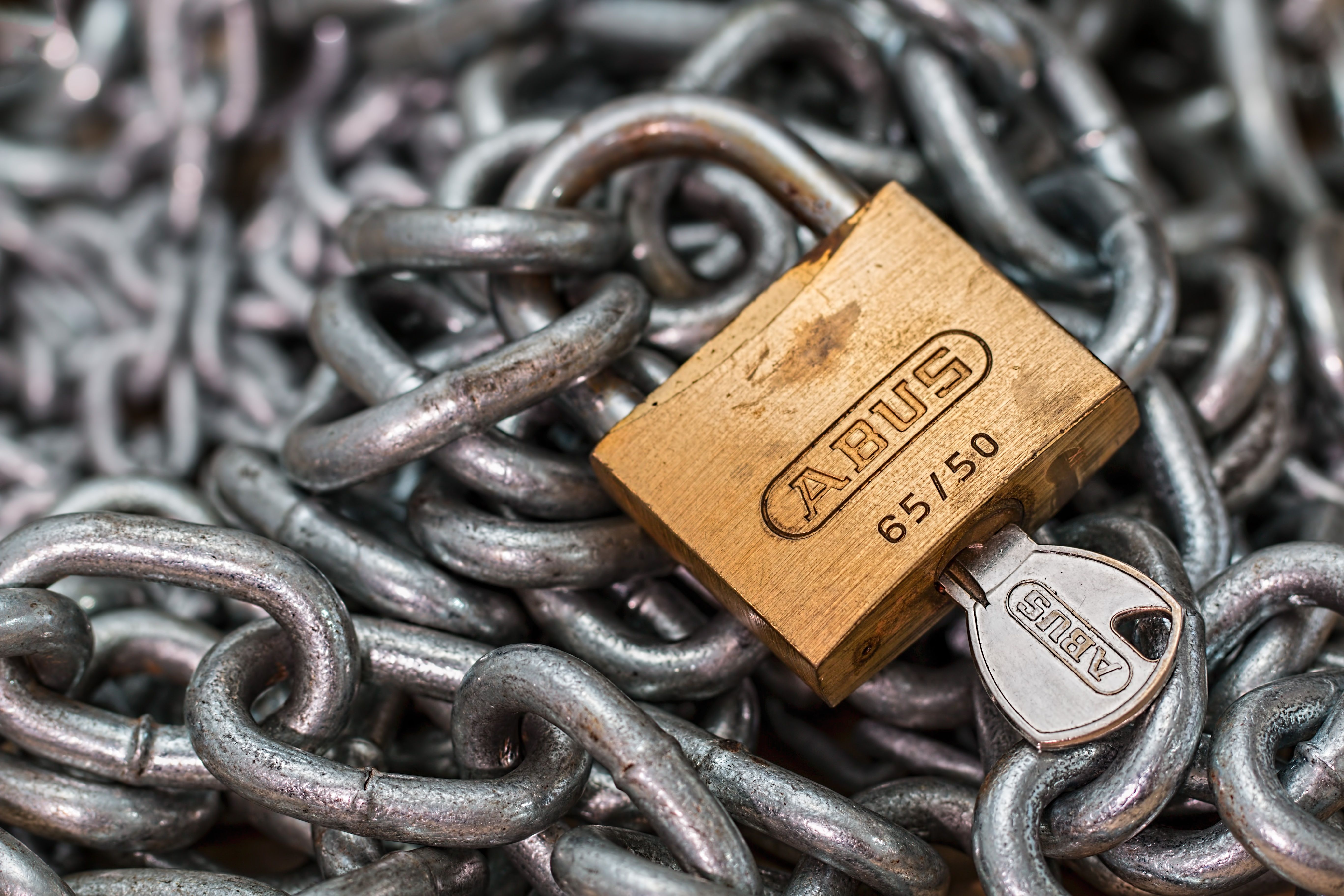 A gold padlock and key resting on a chain, symbolizing access control