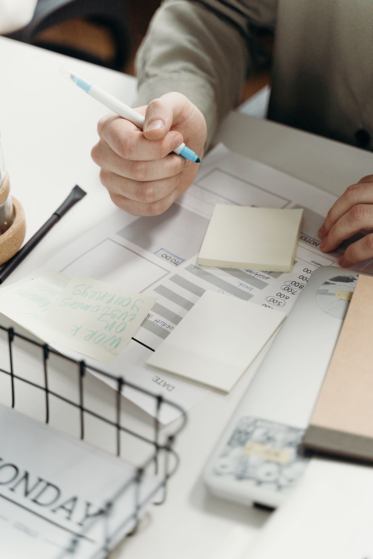 A hand writing a single note on a small piece of paper, the discipline of describing one clear task instead of a long wish list