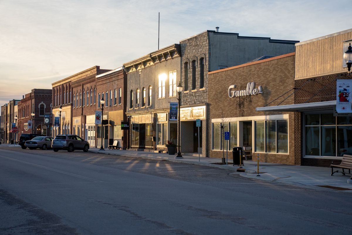 A quiet small-town main street at sunset lined with historic storefronts
