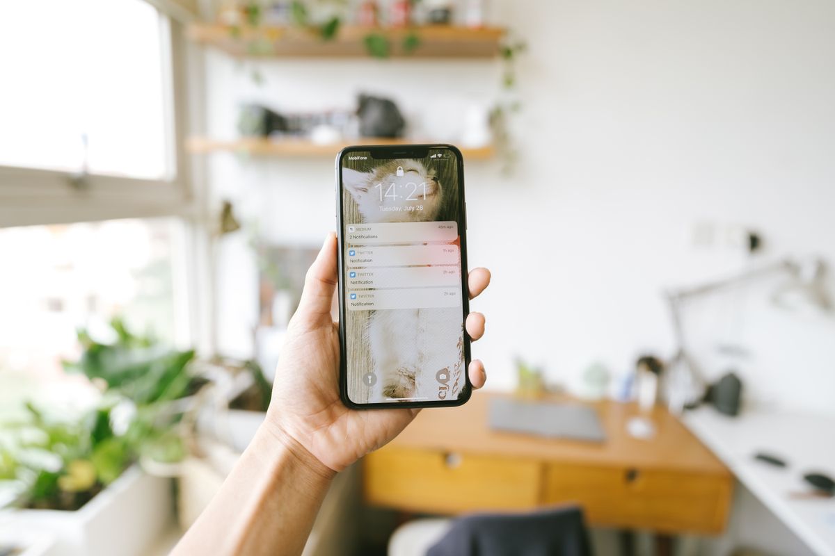 A hand holding a smartphone showing a notification, in a bright indoor setting